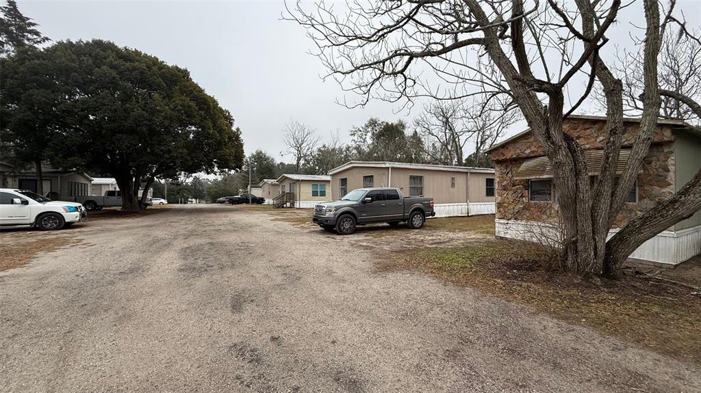 A gravel driveway leads past several mobile homes and parked trucks under bare trees — 12656 SE 78TH TERRACE, BELLEVIEW, FL