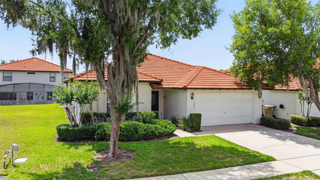A single-story house with a white stucco exterior, red tile roof, and a two-car garage — 16801 LAZY BREEZE LOOP, CLERMONT, FL