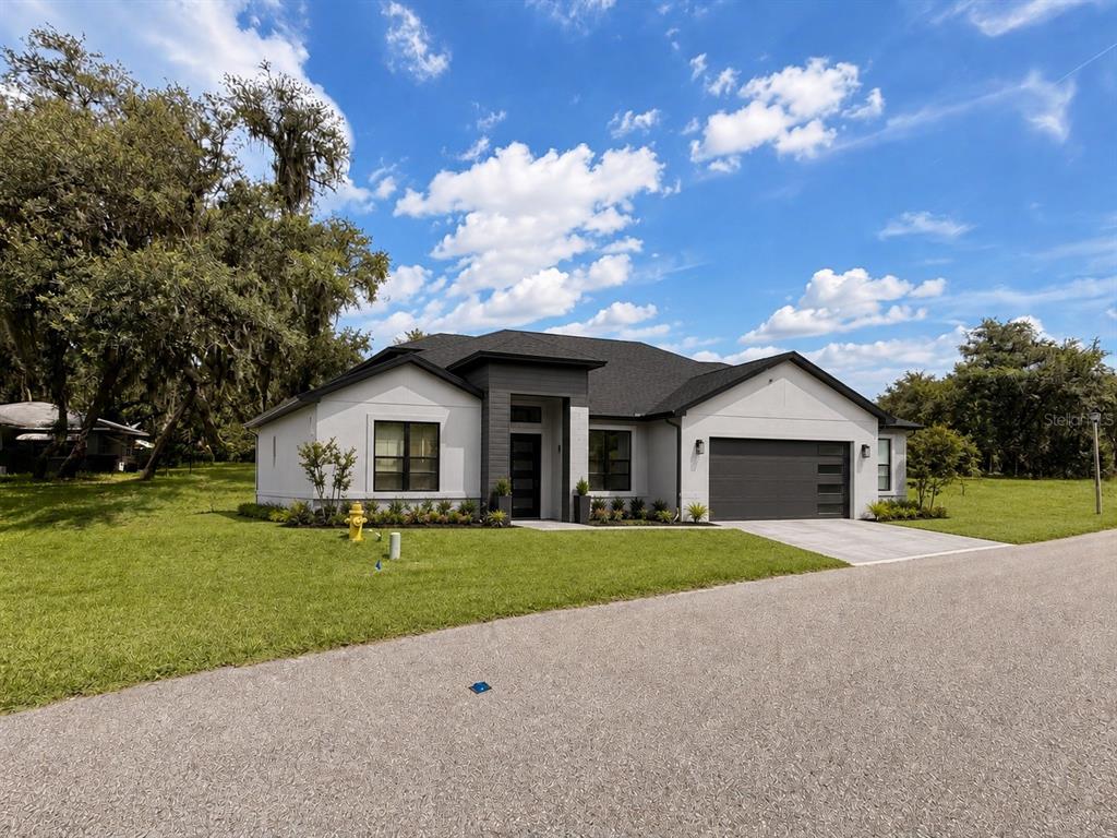 A modern single-story house with a gray garage, white stucco walls, and a dark roof — 5717 SUN VALLEY DRIVE, SEBRING, FL