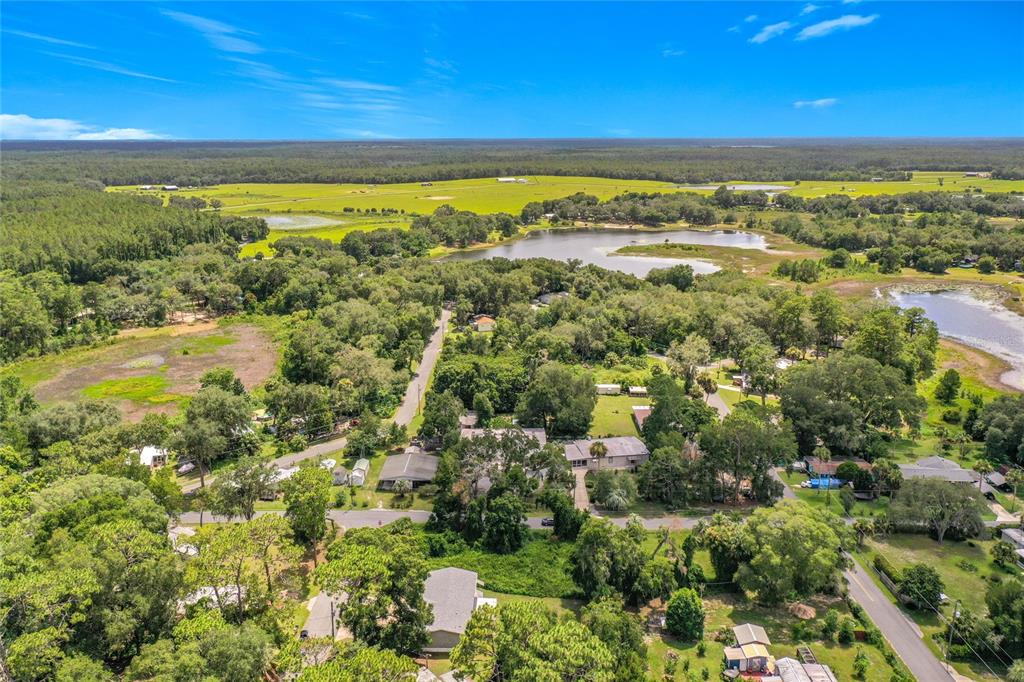 An aerial view shows a rural residential neighborhood surrounded by trees, lakes, and open fields — 0 SE 66TH PLACE, OCKLAWAHA, FL