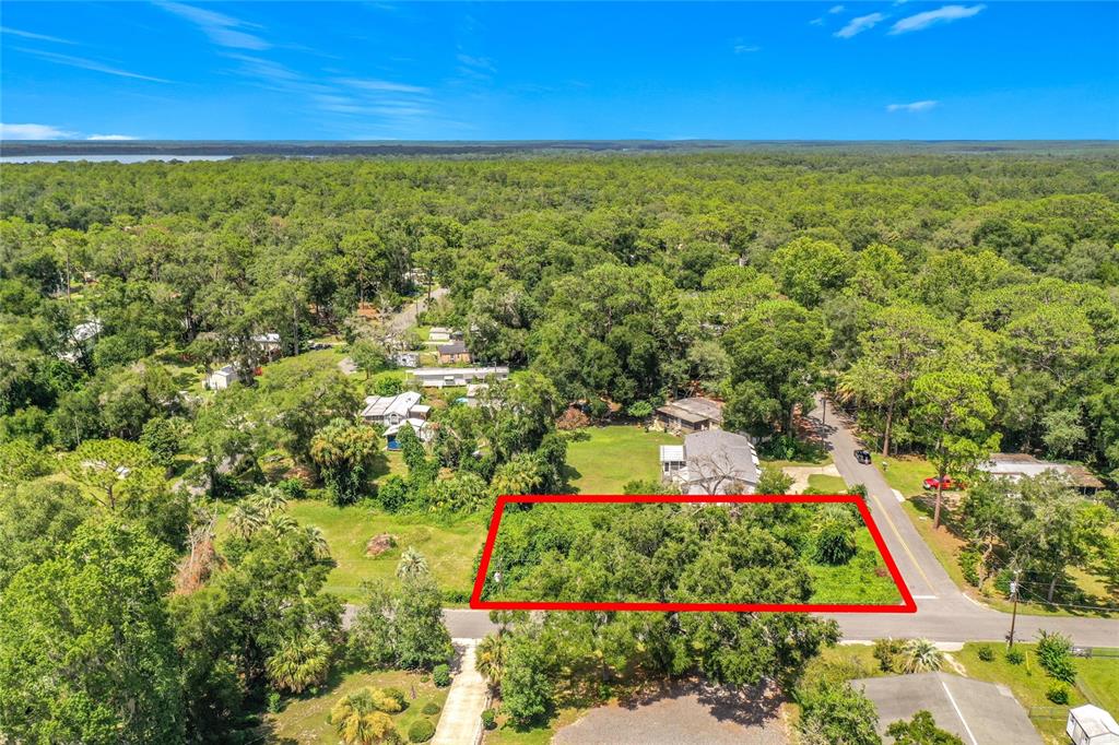An aerial view shows a rectangular, tree-covered vacant lot outlined in red near a road — 0 SE 66TH PLACE, OCKLAWAHA, FL