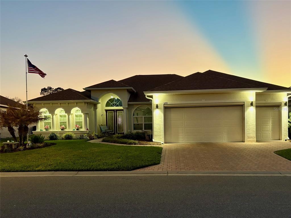 A single-story house with a three-car garage, arched windows, and an American flag outside — 6261 PINEHURST LOOP, WINTER HAVEN, FL