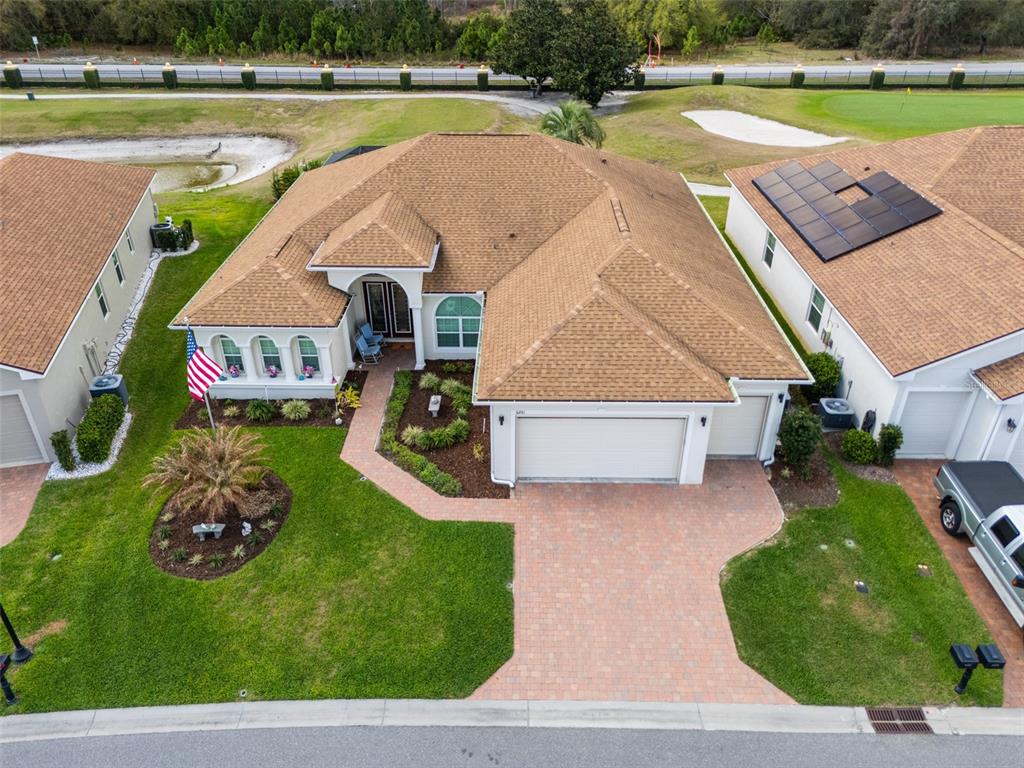 An aerial view shows a single-story house with a brown shingled roof and brick driveway — 6261 PINEHURST LOOP, WINTER HAVEN, FL