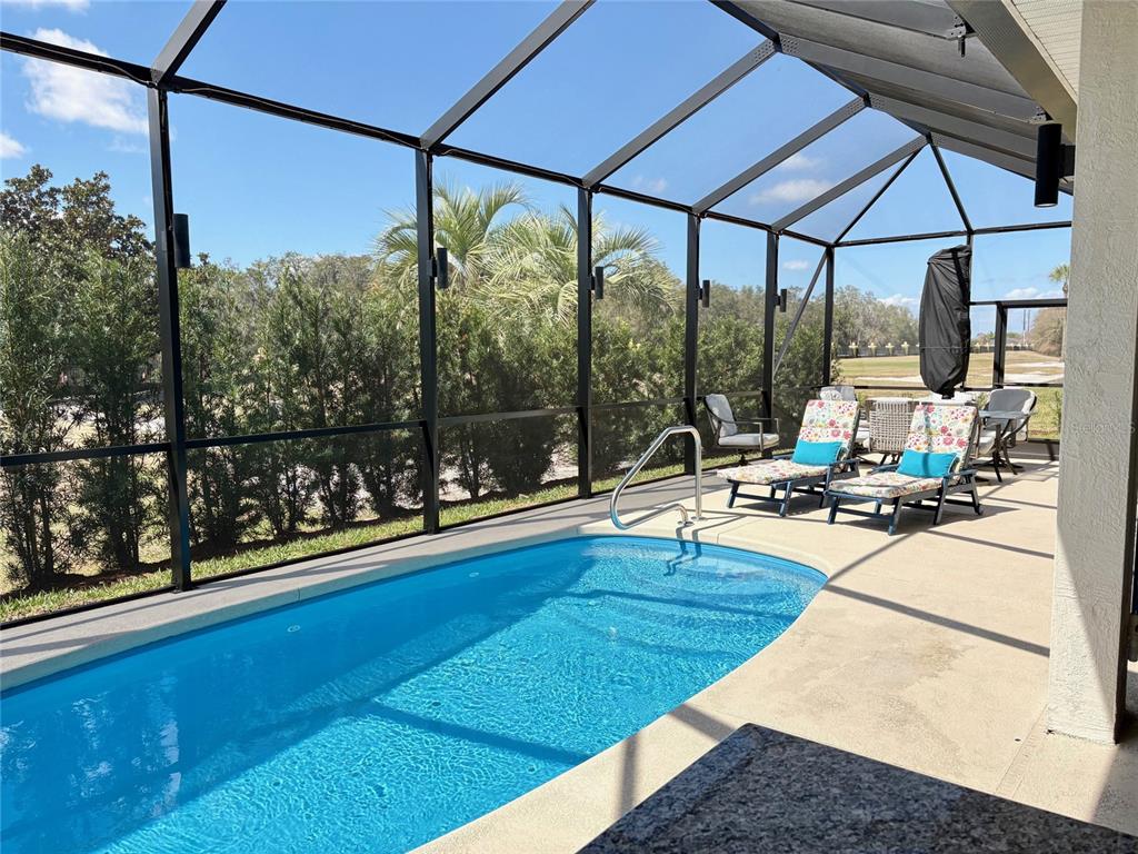 A screened-in pool patio features lounge chairs, a concrete deck, and views of landscaping — 6261 PINEHURST LOOP, WINTER HAVEN, FL