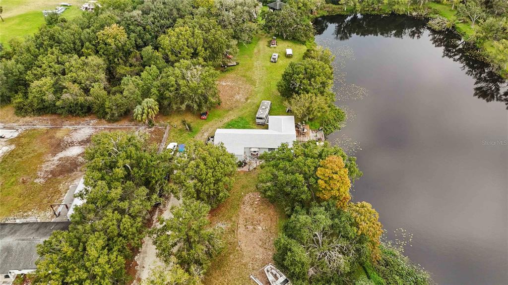 An aerial view shows a house situated on a large lot next to a lake — 8011 41ST AVENUE E, BRADENTON, FL