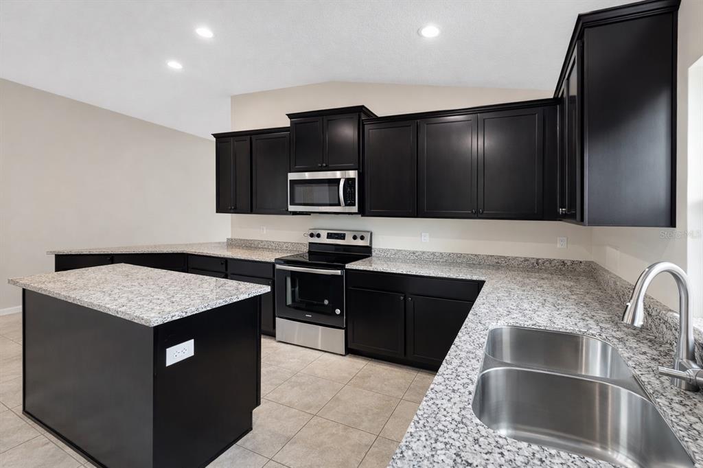 A dining area with beige carpet and walls features a chandelier and a kitchen view — 7544 BENT TREE LOOP, ST CLOUD, FL