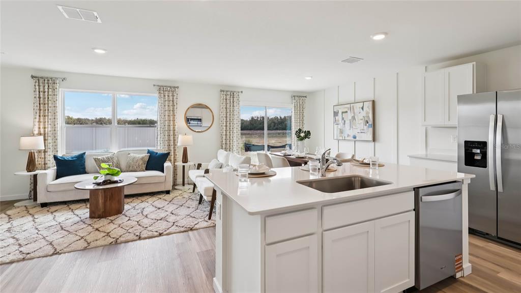 An open-concept kitchen and living area features white cabinetry, stainless appliances, and a large island — 11008 NW 167TH TERRACE, ALACHUA, FL