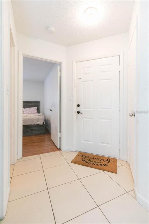 A tiled entryway features a white front door, a welcome mat, and a bedroom doorway — 8636 MALLARD RESERVE DRIVE UNIT 201, TAMPA, FL