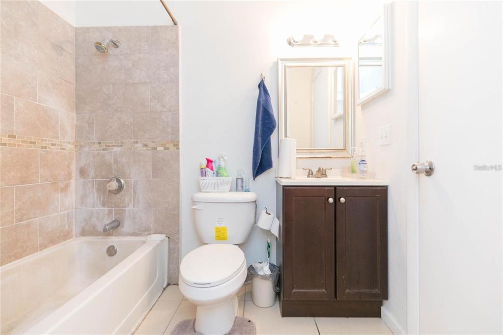 A bathroom features a tiled shower-tub combo, a white toilet, and a dark wood vanity — 8636 MALLARD RESERVE DRIVE UNIT 201, TAMPA, FL