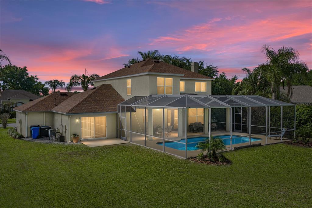 A two-story house with a screened-in pool and patio area at sunset — 5104 WHISPERING LEAF TRAIL, VALRICO, FL