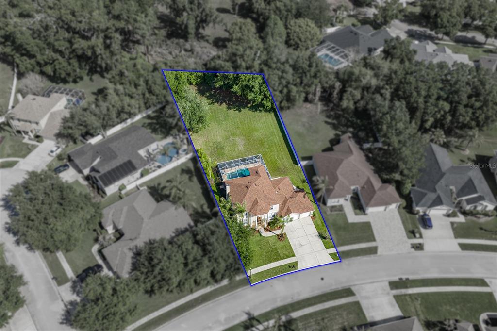 An aerial view shows a house with a pool and a large backyard outlined in blue — 5104 WHISPERING LEAF TRAIL, VALRICO, FL