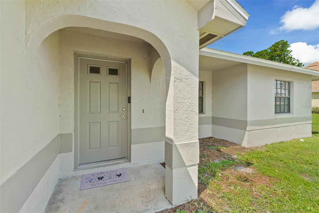 An exterior view of a house entrance with a beige door and arched porch — 14 BALLARD LANE, PALM COAST, FL
