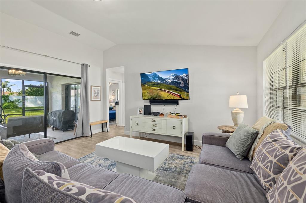 A living room features a gray sectional sofa, white coffee table, and a wall-mounted television — 14 BALLARD LANE, PALM COAST, FL
