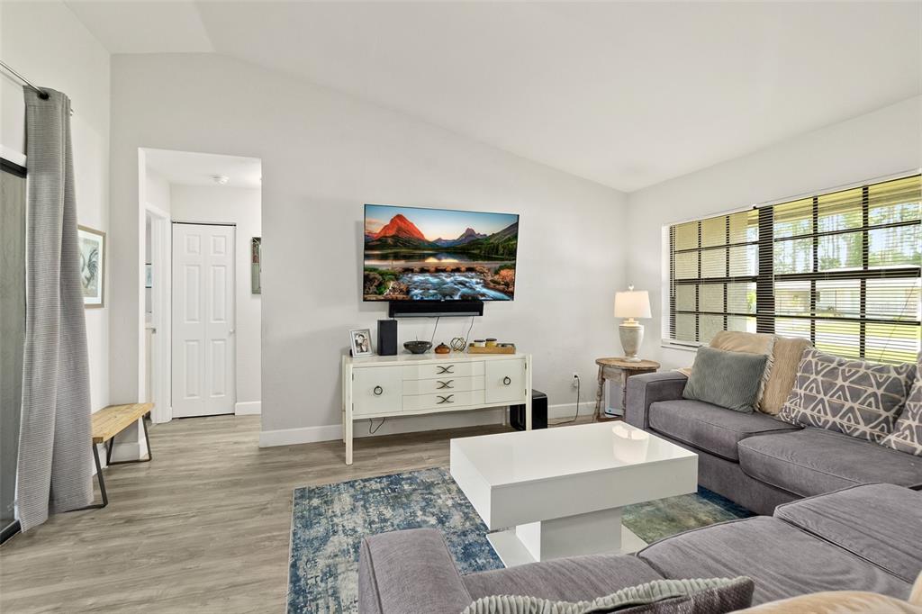A living room features a grey sectional sofa, a white coffee table, and a wall-mounted television — 14 BALLARD LANE, PALM COAST, FL