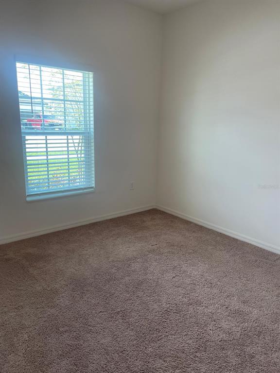 A bedroom with white walls, beige carpet, and a window with white blinds — 13470 LEAPING WATER WAY, ASTATULA, FL