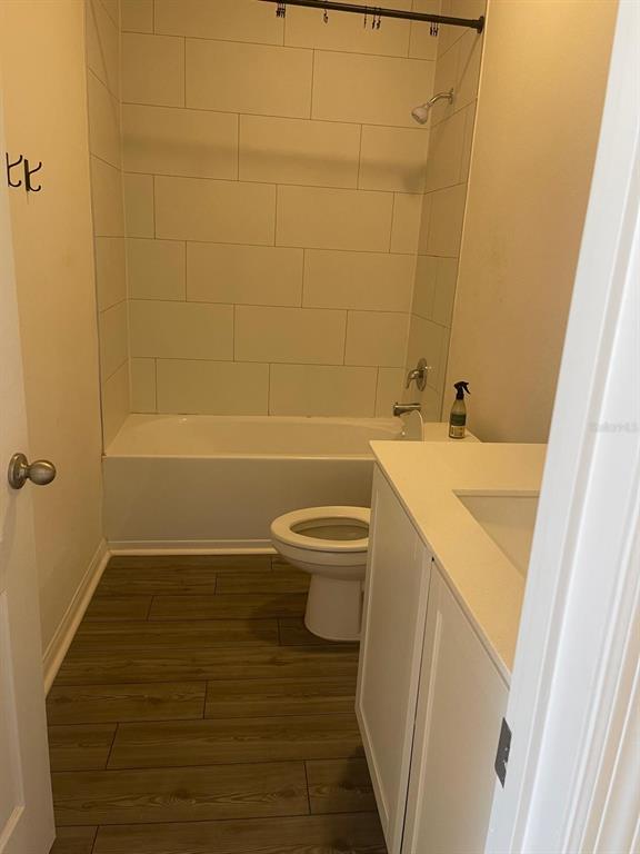 A bathroom features a white vanity, a toilet, and a bathtub with tiled walls — 13470 LEAPING WATER WAY, ASTATULA, FL