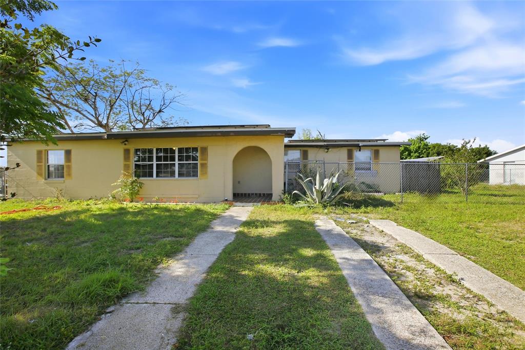 A single-story yellow house with a flat roof, arched entryway, and a concrete driveway — 21585 OLEAN BOULEVARD, PORT CHARLOTTE, FL