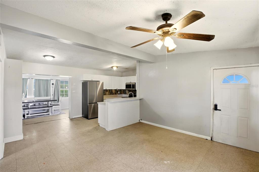 A kitchen with white cabinets and stainless steel appliances opens to a dining area — 21585 OLEAN BOULEVARD, PORT CHARLOTTE, FL