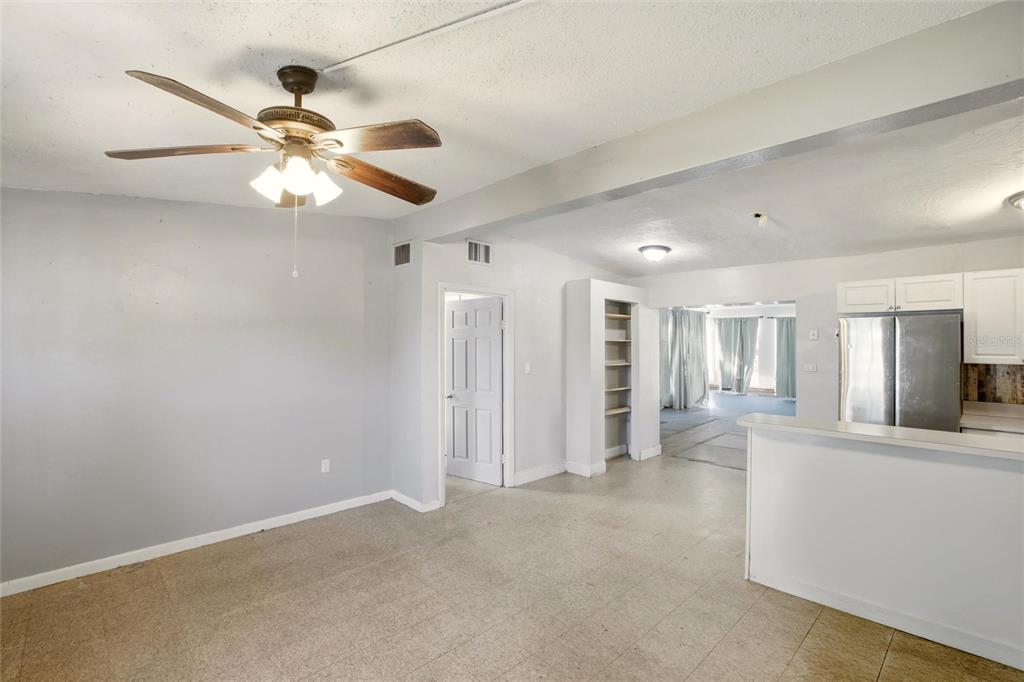 A room with a ceiling fan, light gray walls, tile flooring, and an open kitchen — 21585 OLEAN BOULEVARD, PORT CHARLOTTE, FL