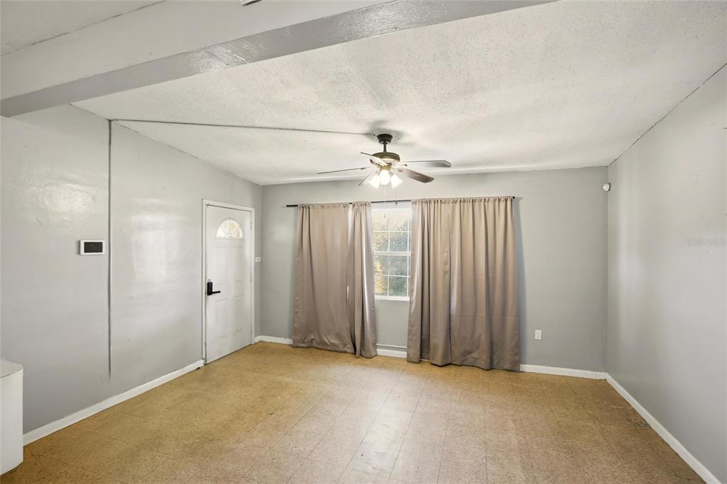 A living room features light gray walls, a ceiling fan, and beige square floor tiles — 21585 OLEAN BOULEVARD, PORT CHARLOTTE, FL