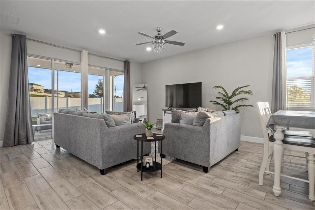 A living room with gray sofas, a ceiling fan, and sliding glass doors to a patio — 1804 VISTA VIEW DRIVE, DUNDEE, FL