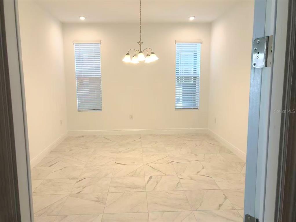 A dining room with white walls, a chandelier, two windows, and light-colored marble-look tile flooring — 2578 TRIELLE AVENUE, KISSIMMEE, FL