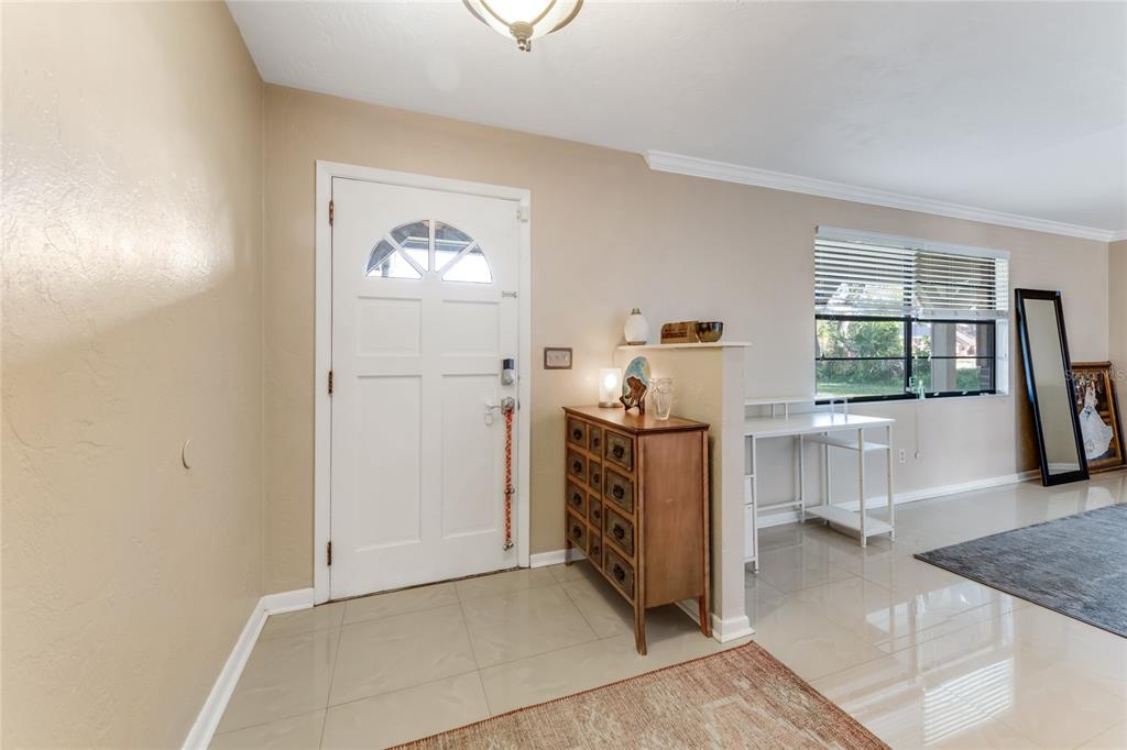 An entryway features a white front door, a wooden chest, and a desk near a window — 800 W RIVER OAK DRIVE, ORMOND BEACH, FL