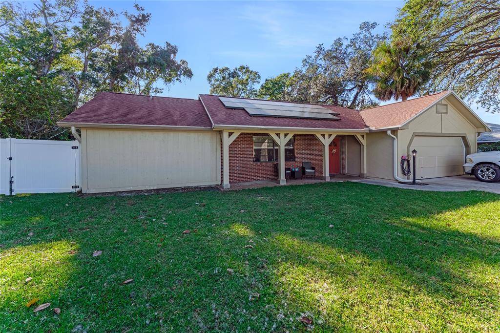 A single-story brick and siding house with solar panels on the roof and a garage — 800 W RIVER OAK DRIVE, ORMOND BEACH, FL