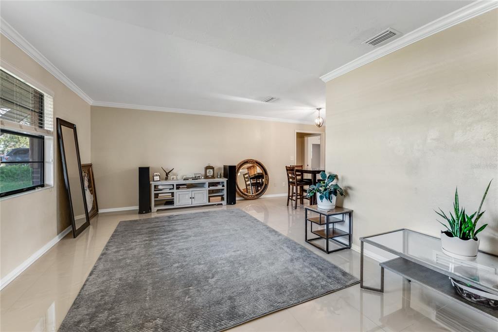 A living room with light tile floors, a large gray rug, and neutral-colored walls — 800 W RIVER OAK DRIVE, ORMOND BEACH, FL