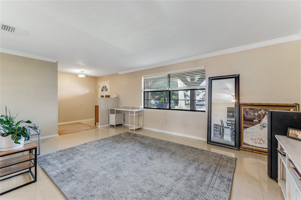 A living room with light tile floors, a large gray rug, and a desk area — 800 W RIVER OAK DRIVE, ORMOND BEACH, FL