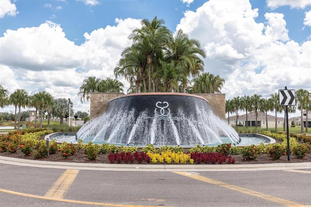 A large circular fountain with a stone wall and palm trees sits in a roundabout — 17066 OVAL RUM DRIVE, WIMAUMA, FL