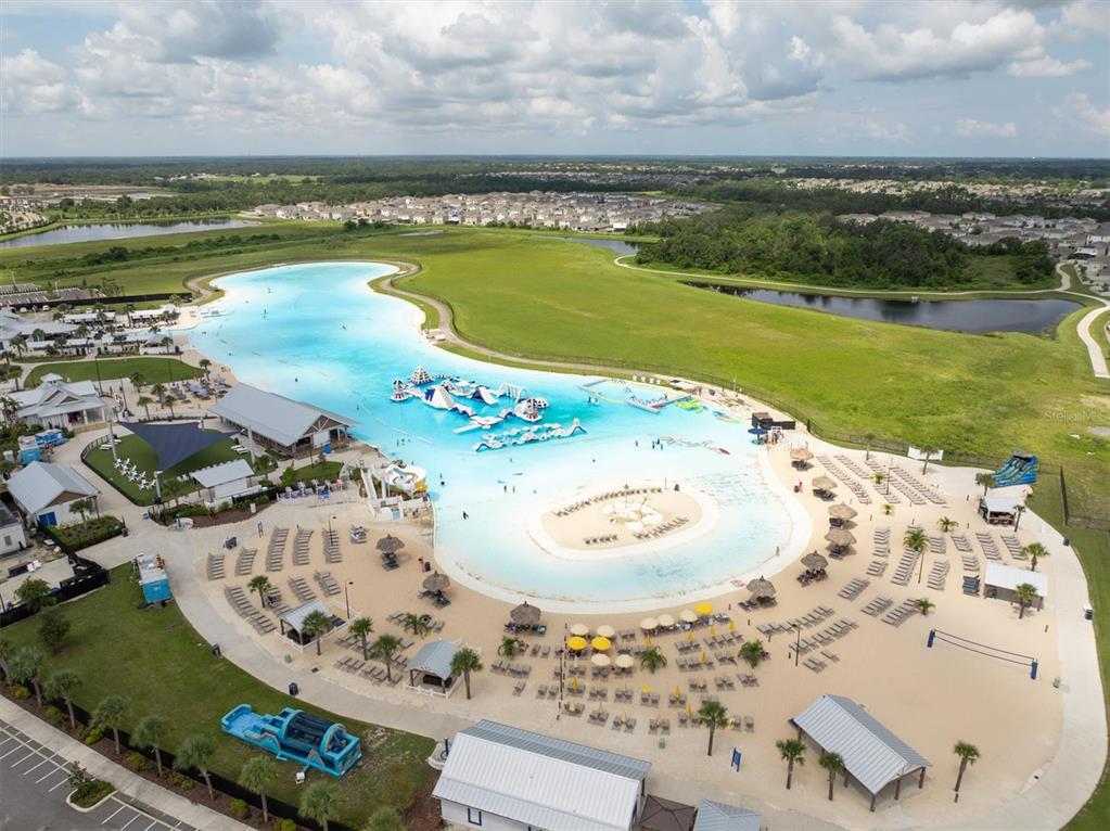 An aerial view of a large man-made turquoise lagoon with a sandy beach and amenities — 17066 OVAL RUM DRIVE, WIMAUMA, FL
