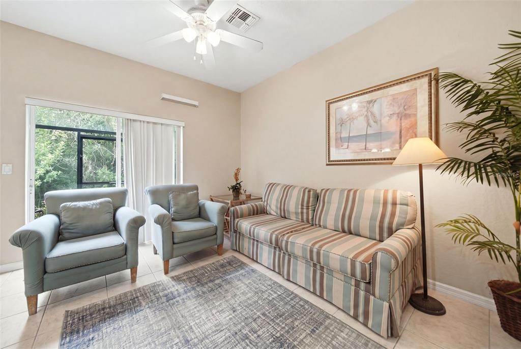 A living room features a striped sofa, two blue armchairs, a rug, and a ceiling fan — 2402 CARAVELLE CIRCLE, KISSIMMEE, FL