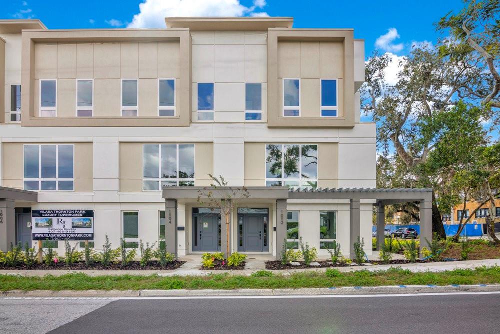 The exterior of a modern multi-story townhouse complex features a light-colored facade and gray doors — 1010 E ROBINSON STREET, ORLANDO, FL