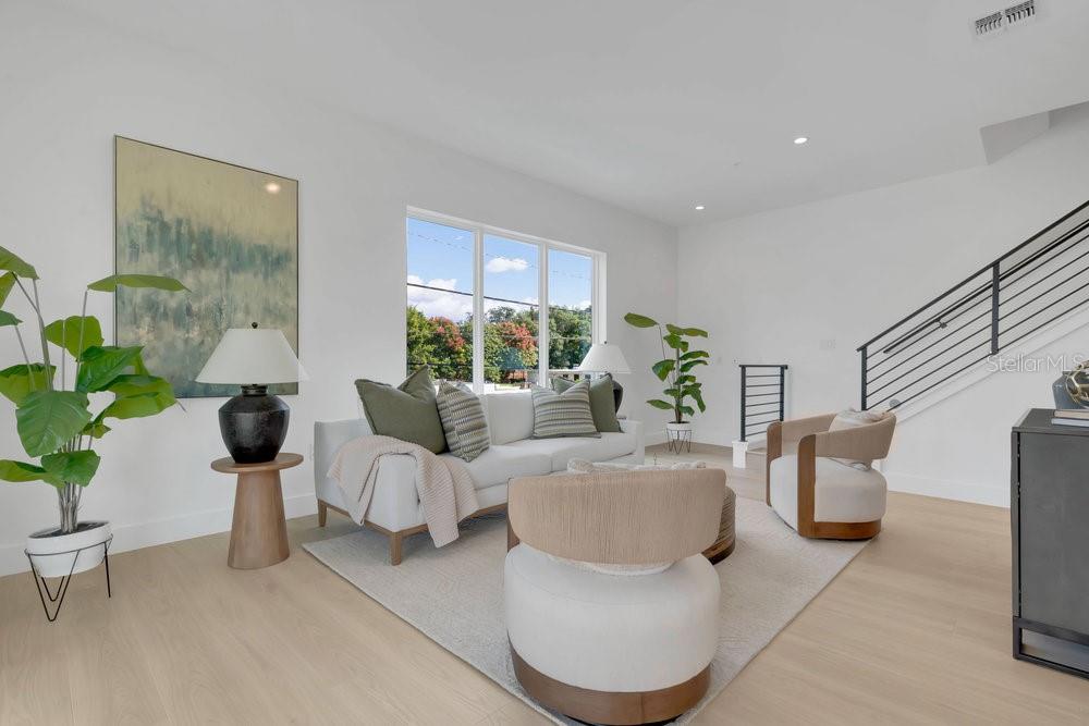A modern living room features a white sofa, two accent chairs, and light wood flooring — 1010 E ROBINSON STREET, ORLANDO, FL