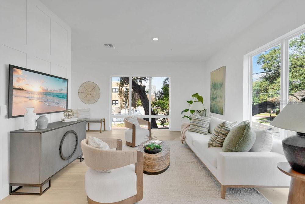A bright living room features white walls, a sofa, two armchairs, and a large window — 1010 E ROBINSON STREET, ORLANDO, FL