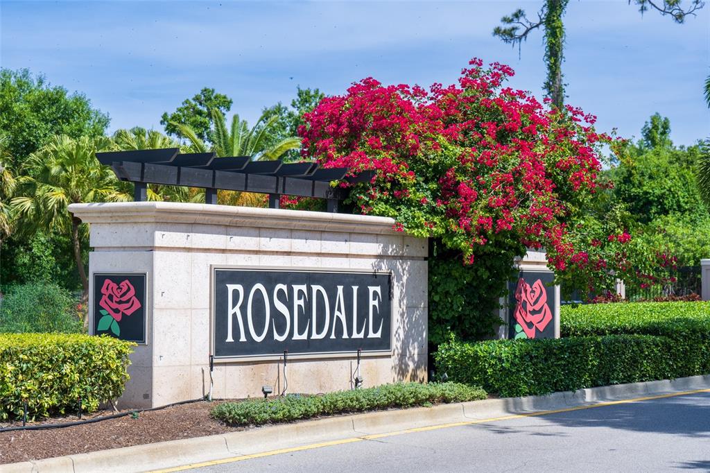 A stone entrance sign for Rosedale stands behind a manicured hedge with blooming bougainvillea — 4703 TOBERMORY WAY, BRADENTON, FL