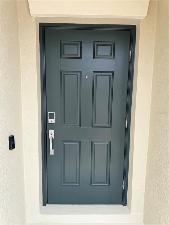 A close-up view of a dark green front door with a chrome handle and keypad — 16491 GLASSY LOCH LOOP, CLERMONT, FL