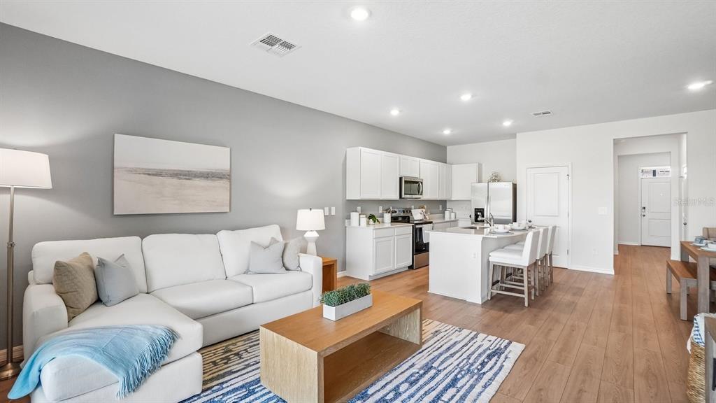 An open-concept living room and kitchen featuring white cabinetry, a kitchen island, and wood flooring — 12605 CITRUS PARK LANE, TAMPA, FL