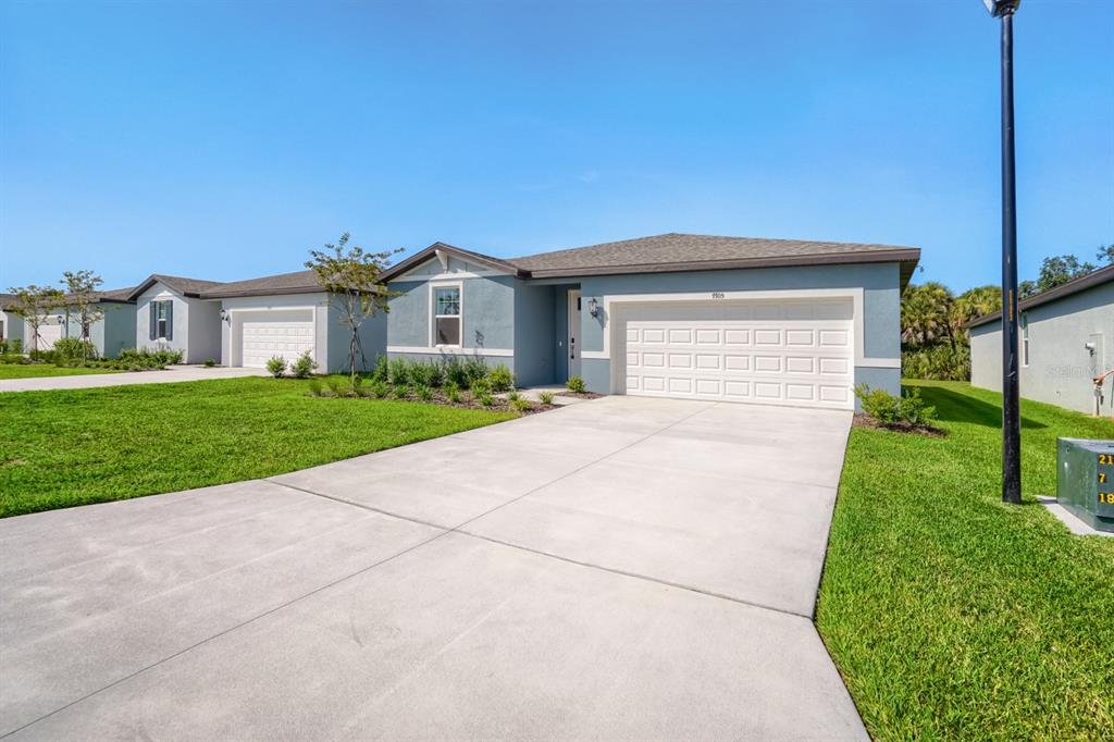 A single-story house with a blue exterior, a two-car garage, and a concrete driveway — 7705 SATTERFIELD TERRACE, PARRISH, FL