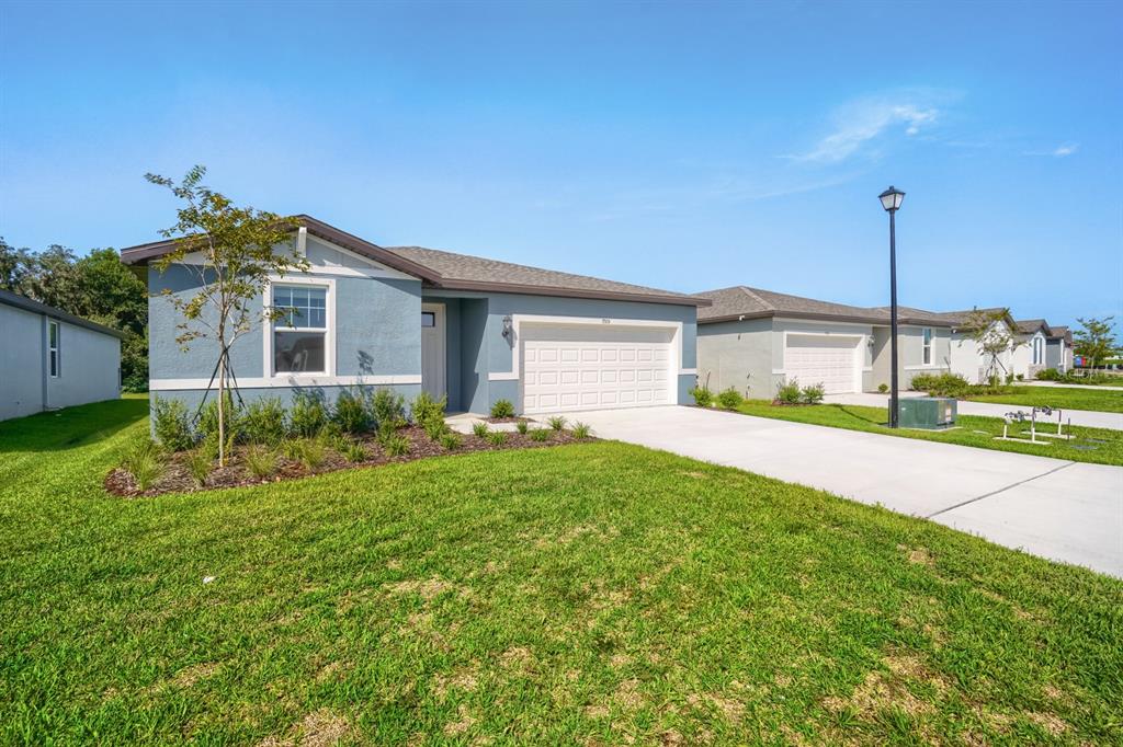 A blue single-story house with a two-car garage and a front lawn — 7705 SATTERFIELD TERRACE, PARRISH, FL