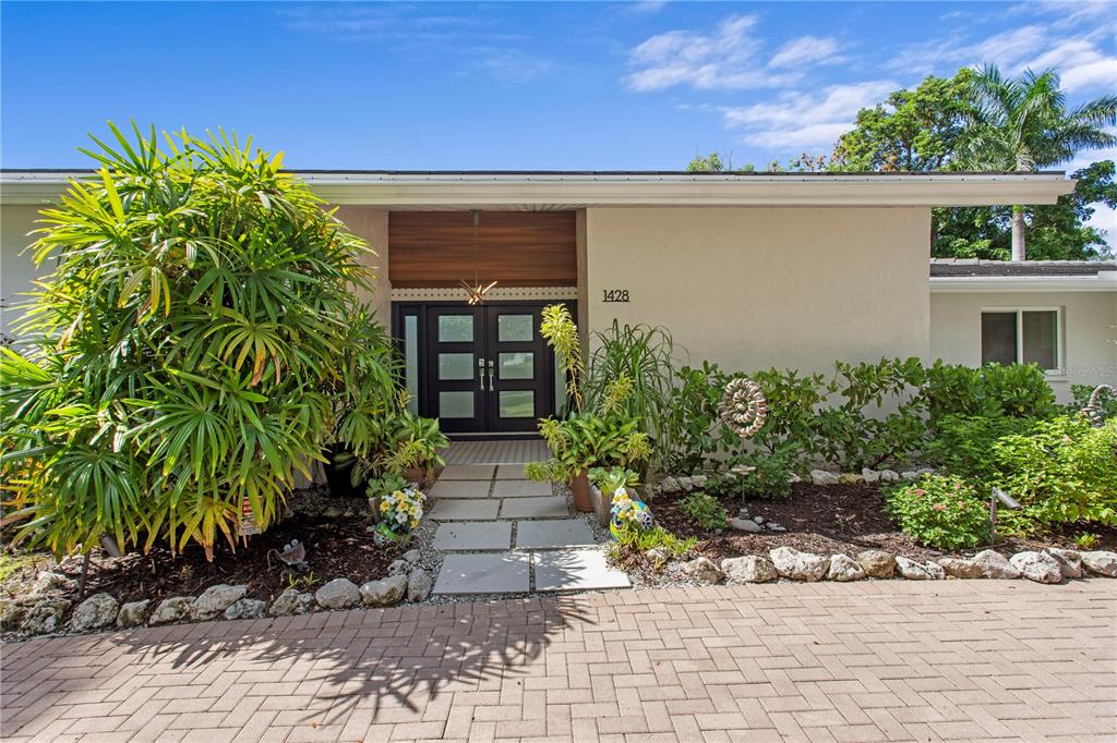An aerial view shows a single-story house with a screened-in pool and a gray roof — 1428 PINE BAY DRIVE, SARASOTA, FL