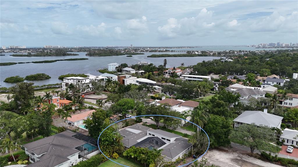A low-slung, light-colored house is framed by a large, sprawling oak tree in the foreground — 1428 PINE BAY DRIVE, SARASOTA, FL