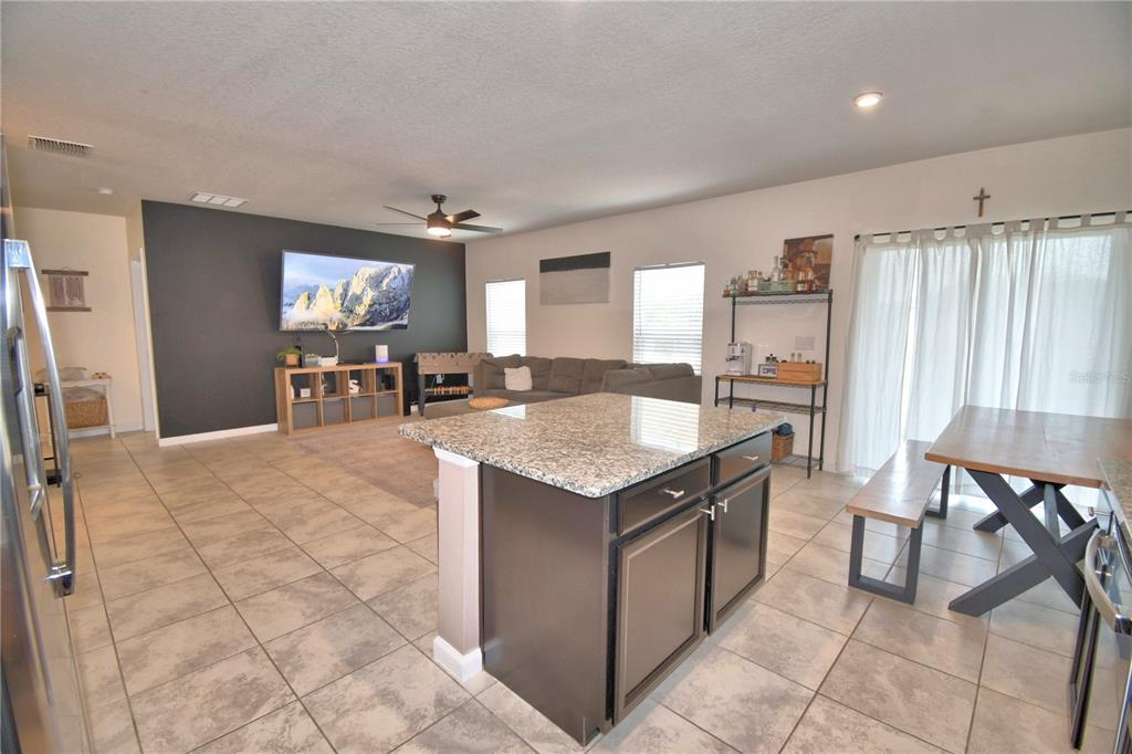 An open-concept living area features a kitchen island, tile flooring, and a dark accent wall — 542 EAGLE LANDING BOULEVARD, WINTER HAVEN, FL