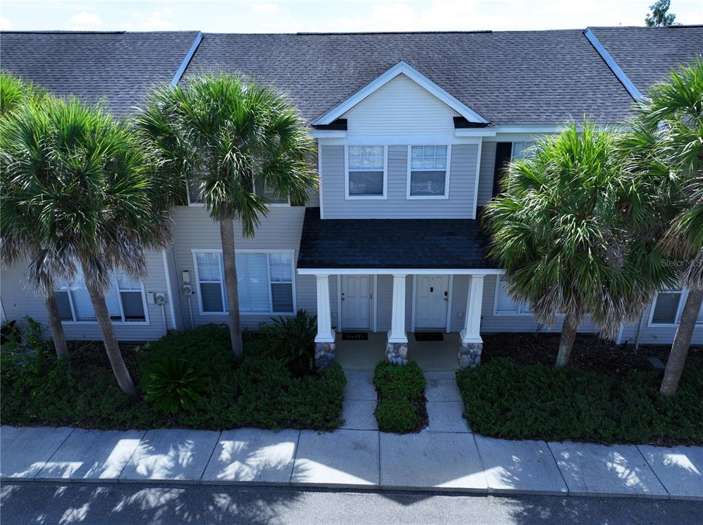 An exterior view of a two-story townhouse with light siding, palm trees, and a porch — 12207 COUNTRY WHITE CIRCLE, TAMPA, FL