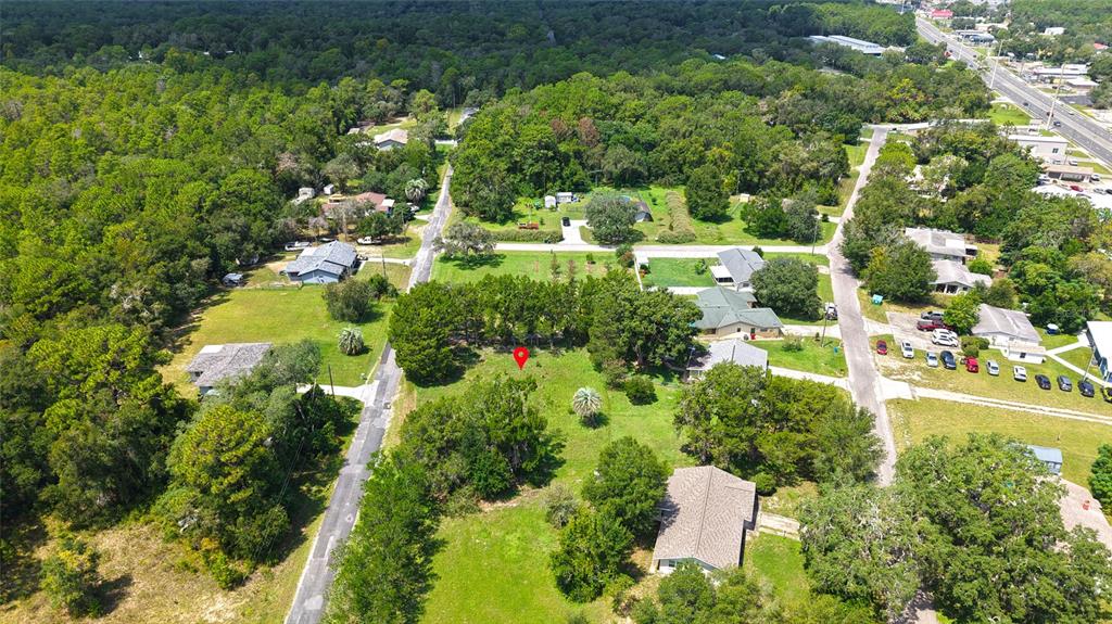 An aerial view shows a vacant, tree-lined residential lot marked with a red location pin — 3577 E KIRBY LANE, INVERNESS, FL