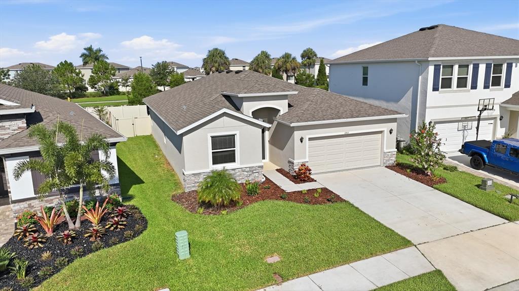 An aerial view shows a single-story house with a tan stucco exterior and a garage — 12413 DORA TRAIL, PARRISH, FL