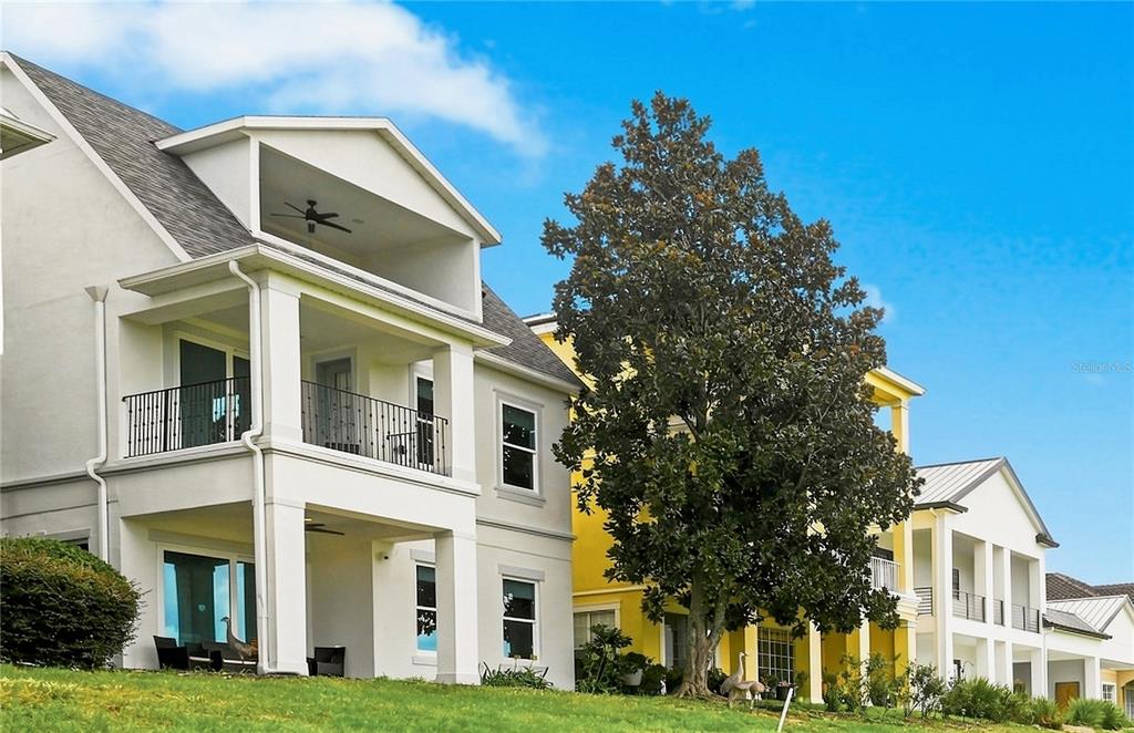 A two-story house with a white stucco exterior and two gray arched garage doors — 1530 COROLLA COURT, REUNION, FL