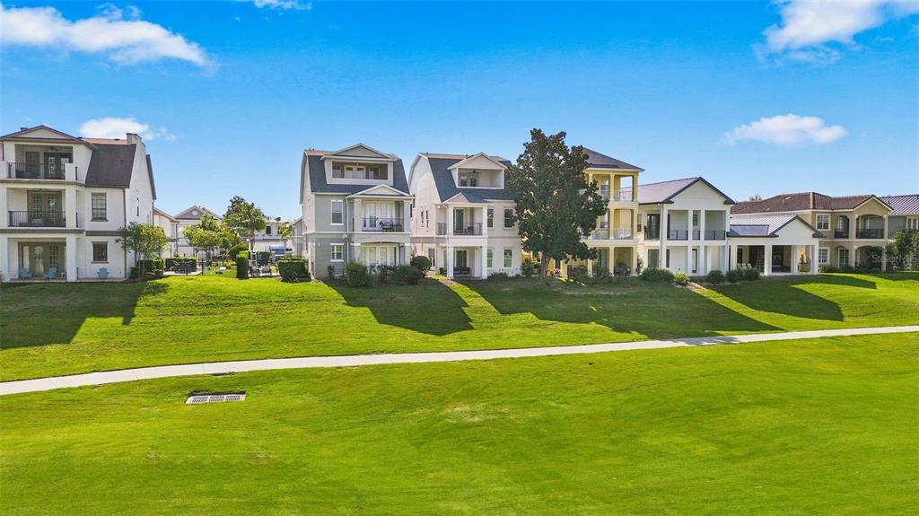 A two-story white house with two gray arched garage doors and a brick driveway — 1530 COROLLA COURT, REUNION, FL