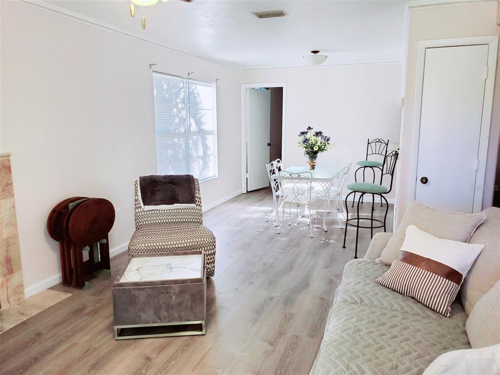 A living and dining area features light wood-look flooring, white walls, and a white table — 3773 59TH AVENUE W, BRADENTON, FL